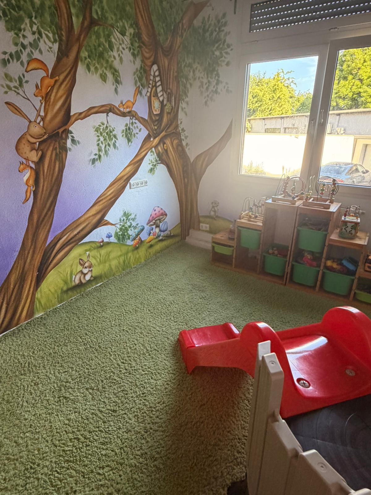 Spielzimmer mit Waldwand, Teppich und Holzregalen
